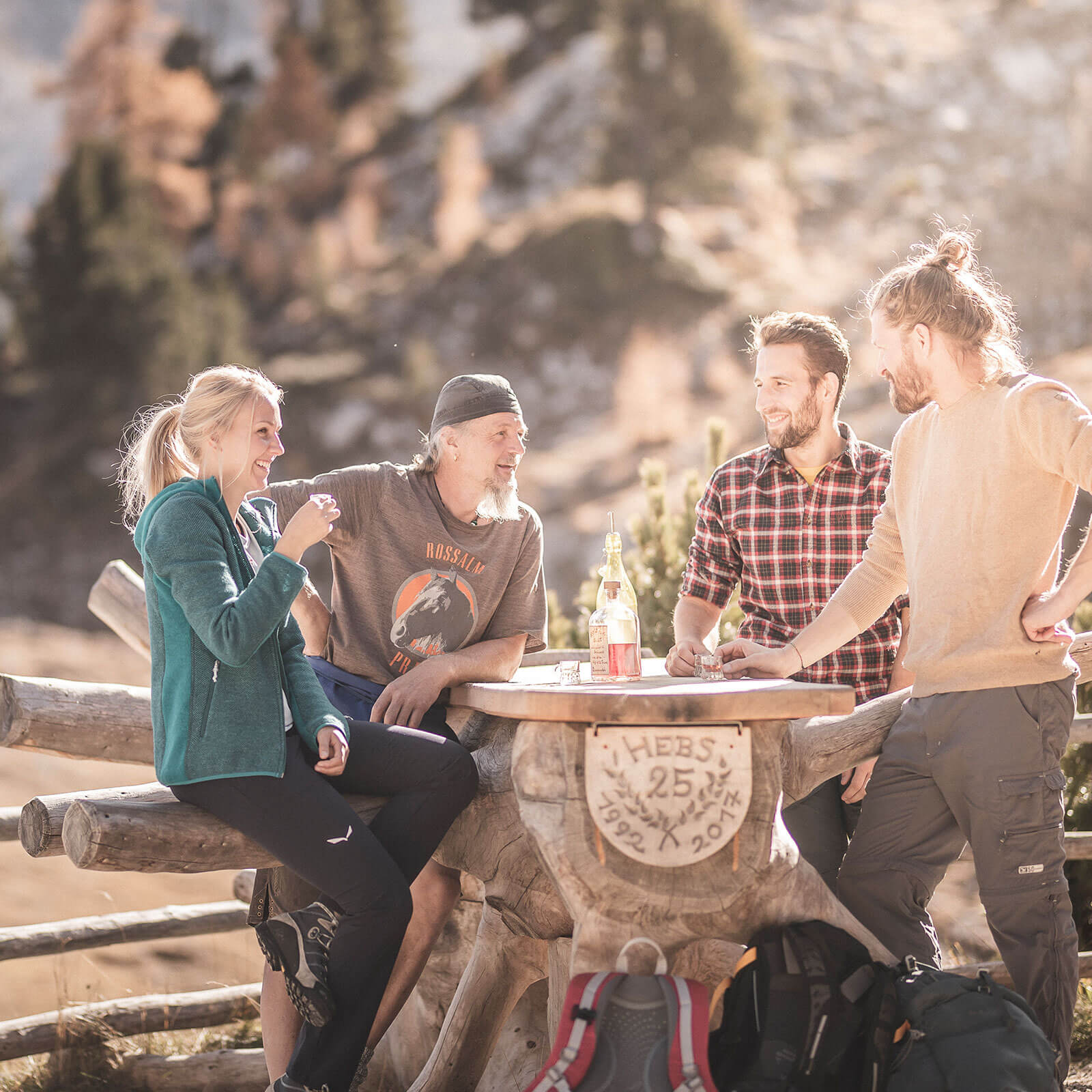 Vier Wanderer trinken einen Schnaps bei einer Alm