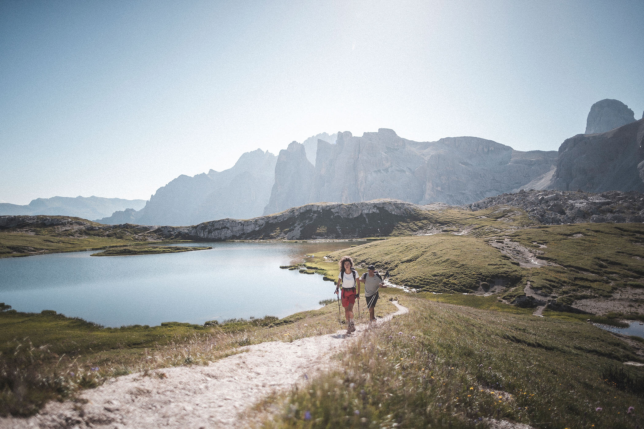 Zwei Wanderer gehen an einem Bergsee vorbei