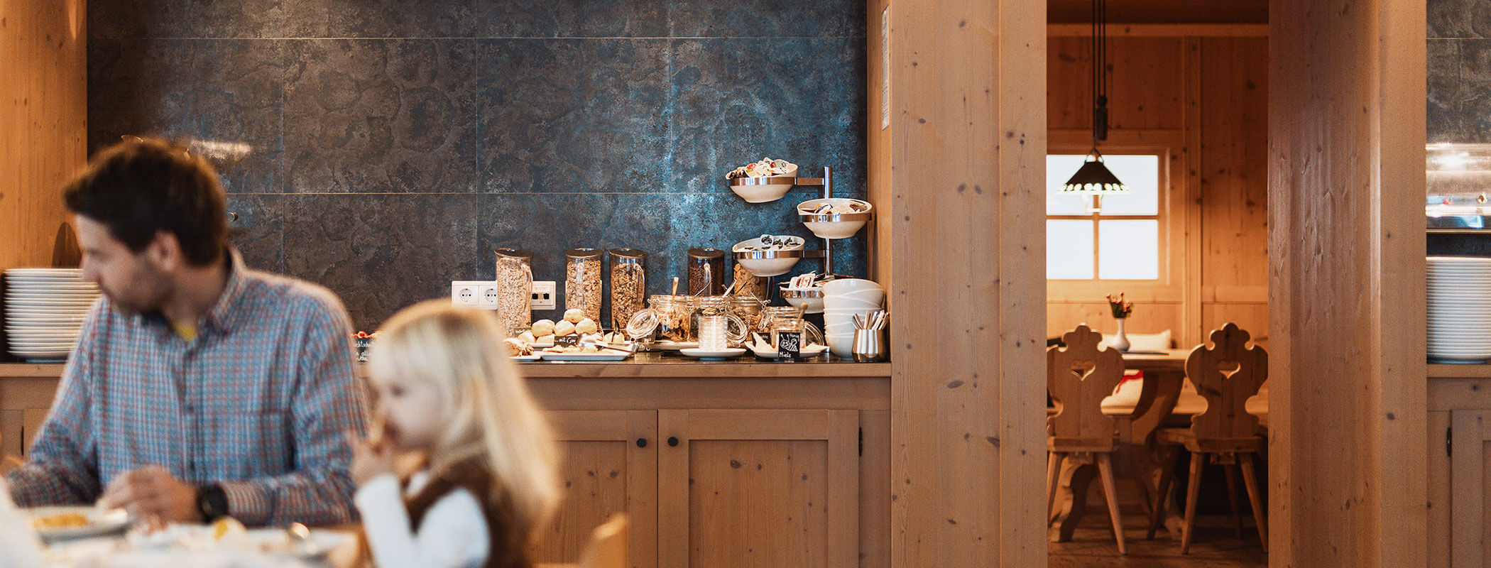 Familie beim Frühstück, dahinter das Frühstücksbuffet