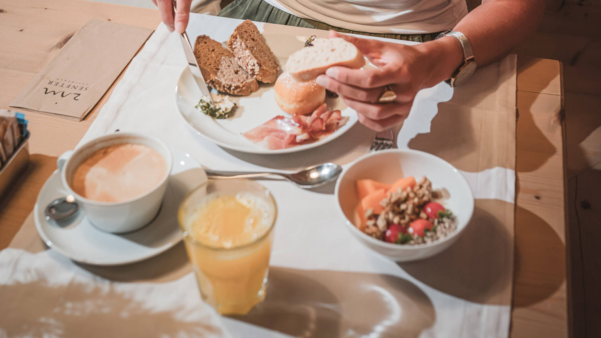 Woman having breakfast with orange juice, bread, salmon, and coffee