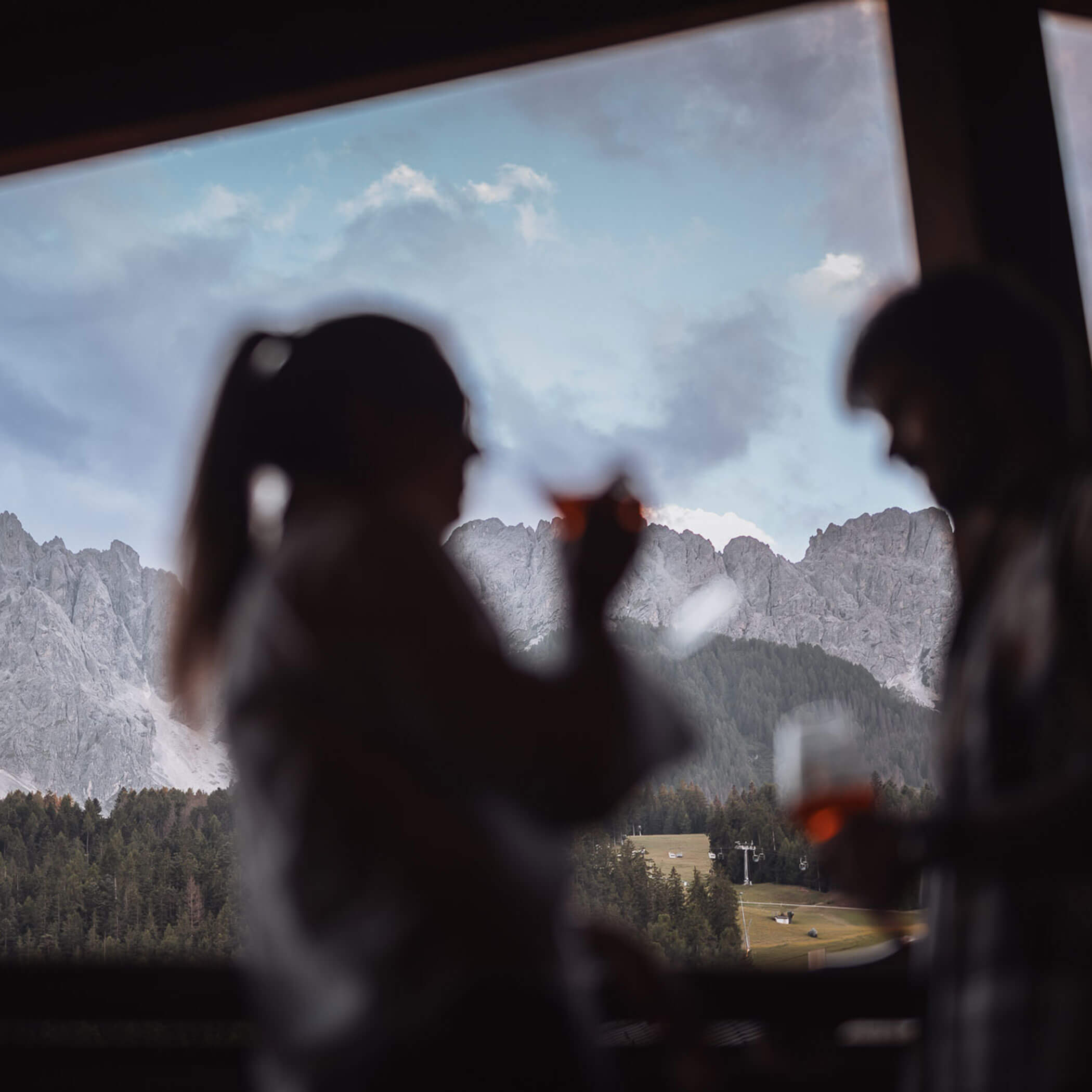 Silhouetten einer Frau und eines Mannes, dahinter die Dolomiten